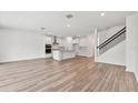 Open-concept living space featuring hardwood floors, a staircase, and a view into the modern kitchen at 1219 Kazaz Ct, Zephyrhills, FL 33540