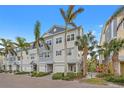 Attractive three-story townhome exterior boasts beachy colors, garage, and tropical landscaping with palm trees at 192 Haven Beach Dr, Indian Rocks Beach, FL 33785