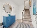 Bright foyer with staircase, tiled floor, and decorative chest under a mirror exudes elegance at 192 Haven Beach Dr, Indian Rocks Beach, FL 33785