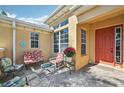 The home has a front porch with outdoor seating, paver flooring, and a bright red front door at 2471 Kensington Greens Dr, Sun City Center, FL 33573