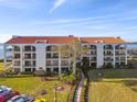 Beautiful condo building with a red tile roof, manicured lawn, and bay views at 301 Mariner Dr # 301, Tarpon Springs, FL 34689