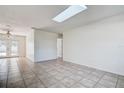 Open-concept living area featuring neutral tile flooring, a bright skylight, and ample natural light at 4570 69Th N Ave, Pinellas Park, FL 33781