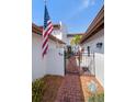 Inviting gated entrance with a brick walkway leading to a charming home adorned with an American flag at 7501 Cumberland Rd # 22, Seminole, FL 33777