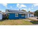 Charming single-story home showcasing a blue painted exterior, solar panels, and a well-manicured lawn at 8903 Bay Bridge Ct, Tampa, FL 33634