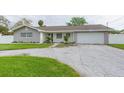 Gray house with white accents, a two-car garage, and well-manicured lawn at 1613 Druid E Rd, Clearwater, FL 33756