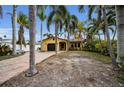 House exterior, showcasing a yellow house with palm trees and a brick driveway at 311 15Th Ave, Indian Rocks Beach, FL 33785