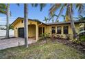 A yellow house with a dark garage door and lush landscaping at 311 15Th Ave, Indian Rocks Beach, FL 33785