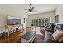 Open living room boasts hardwood floors, a ceiling fan, and sliding doors leading to a balcony at 7532 Marsh Orchid Cir # 8-201, Bradenton, FL 34203