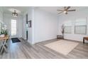 Bright, open-concept living room with gray wood floors, modern ceiling fan, and natural light from large windows at 12625 Horseshoe Bend Dr, Lithia, FL 33547