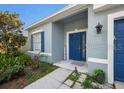 View of a light blue house showcasing a neat front garden, blue door and shutters at 20327 Merry Oak Ave, Tampa, FL 33647