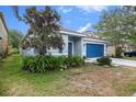 Inviting one-story house with pretty light blue exterior, blue garage door, and lush greenery at 20327 Merry Oak Ave, Tampa, FL 33647