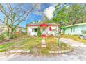 A single-story white home trimmed in red featuring a quaint walkway, healthy lawn, and flourishing landscaping at 5308 Ben Hur Dr, St Petersburg, FL 33708