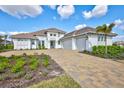 Elegant front exterior with a three-car garage, beautiful landscaping, and a brick driveway at 1201 Blue Shell Loop, Sarasota, FL 34240