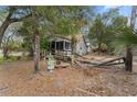 Quaint home with a screened-in porch and damaged wooden walkway surrounded by trees and yard debris at 3623 Whittier St, Tampa, FL 33619