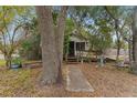 Cozy cottage featuring a screened porch, weathered stairs, and a tranquil garden setting at 3623 Whittier St, Tampa, FL 33619