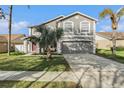 A two-story home with a well-manicured lawn, a large driveway, and well-placed tropical foliage at 5914 Falconwood Pl, Lithia, FL 33547