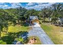 Beautiful aerial view of a home with a large yard surrounded by lush greenery and a long driveway at 11545 Kent Grove Dr, Spring Hill, FL 34610