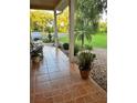 Cozy front porch featuring tiled flooring, potted plants, and a view of the landscaped front yard at 11545 Kent Grove Dr, Spring Hill, FL 34610