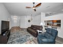 Open living room with wood floors, ceiling fan, and a view into the kitchen with bar seating at 12141 Arron Ter, Trinity, FL 34655