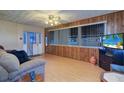 Living room with light wood floors, a sofa, and wood wall paneling at 1235 45Th N St, St Petersburg, FL 33713