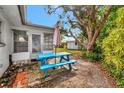 Backyard patio features a bright blue picnic table next to a shaded portion of the yard at 14005 Leeward Dr, Seminole, FL 33776