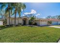 Attractive single-story home with lush green lawn, palm trees, and a two-car garage at 1509 Ventana Dr, Sun City Center, FL 33573