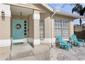 Inviting front porch area with comfortable blue chairs, perfect for relaxing, with decorative door and updated finishes at 2799 Wesleyan Dr, Palm Harbor, FL 34684