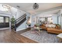 Open-concept living room with hardwood floors, a staircase, leather sofa, and seamless connection to kitchen at 5292 Kernwood Ct, Palm Harbor, FL 34685