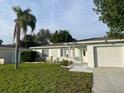 Inviting single-story home featuring a tidy front lawn, lush landscaping, and a two-car garage at 6483 43Rd N Ave, Kenneth City, FL 33709