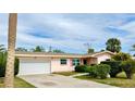 Inviting home featuring a pristine white garage door, complemented by lush greenery and a well-maintained lawn at 2172 University S Dr, Clearwater, FL 33764