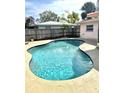 Refreshing pool with a curved design, surrounded by a concrete patio and a well-maintained wooden fence at 2172 University S Dr, Clearwater, FL 33764