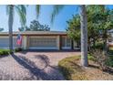 Charming home featuring a brick driveway, attached garage, and lush landscaping at 2609 Locksley St, Sun City Center, FL 33573