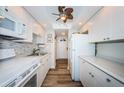 Galley kitchen featuring white cabinetry, modern appliances, and wood-look flooring at 4525 Cove Cir # 805, St Petersburg, FL 33708