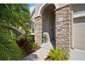 Close up of covered front entry featuring stone columns, lush landscaping, and a welcoming walkway at 7432 Paradiso Dr, Apollo Beach, FL 33572