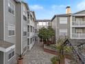 Courtyard of apartments featuring gray siding, white trim, a brick paver walkway, and mature landscaping at 800 S Dakota Ave # 205, Tampa, FL 33606