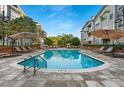 Community pool area, with patio furniture, sun umbrellas, lounge chairs, and a well-maintained pool at 800 S Dakota Ave # 205, Tampa, FL 33606