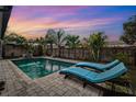 Inviting backyard pool area with brick pavers, sun loungers, and lush tropical landscaping at 1035 County Road 90, Palm Harbor, FL 34684