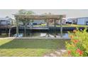 Waterfront view of a private covered boat dock, lift, and grassy yard at 114 W Saint Johns Way, Apollo Beach, FL 33572