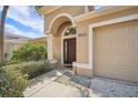 Welcoming front entrance with a covered porch, arched doorway, and meticulously maintained landscaping at 2811 Butterfly Landing Dr, Land O Lakes, FL 34638