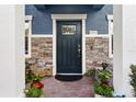 Front door entryway featuring stone accents, brick walkway, and well-maintained landscaping at 28635 Tranquil Lake Cir, Wesley Chapel, FL 33543