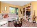 Comfortable living room featuring yellow walls, wood floors, leather furniture, and built-in shelving at 300 Glennes Ln # 208, Dunedin, FL 34698