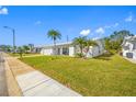 Front view of a white single-story home with palm trees and a well-manicured lawn at 4043 93Rd N Ter, Pinellas Park, FL 33782