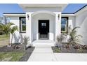 Front entrance of home features a stunning black front door, well-placed lighting, and minimalist landscaping at 5885 114Th N Ter, Pinellas Park, FL 33782