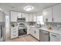 Modern kitchen featuring white cabinets, stainless steel appliances, quartz countertops, and stylish chevron backsplash at 11005 Tyler Dr, Port Richey, FL 34668