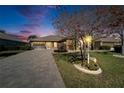 Charming single-story home with brick driveway, well-manicured landscaping, and a welcoming screened in porch at dusk at 1228 Caloosa Creek Ct, Sun City Center, FL 33573