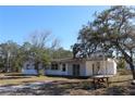 A charming single-story home features a picnic table on a sunny day, set against a backdrop of lush trees and blue sky at 13386 Taylor St, Brooksville, FL 34613