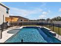 Backyard pool and spa area with fence, deck, umbrella, and outdoor seating, perfect for relaxation at 16733 Glacier Bay Loop, Wimauma, FL 33598