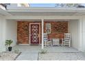 Brick front porch with red door, rocking chairs, and decorative metal art at 2506 Madrid Way S, St Petersburg, FL 33712