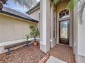 Front entry with brick pathway, wooden bench, and lush landscaping at 26848 Shoregrass Dr, Wesley Chapel, FL 33544