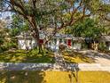 Charming single-story home with a well-manicured lawn and mature trees providing shade at 620 Scotland St, Dunedin, FL 34698